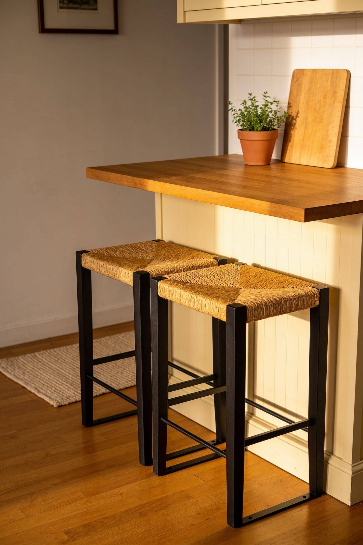 pair of wood saddle counter stools tucked under a kitchen island in a warm rental kitchen