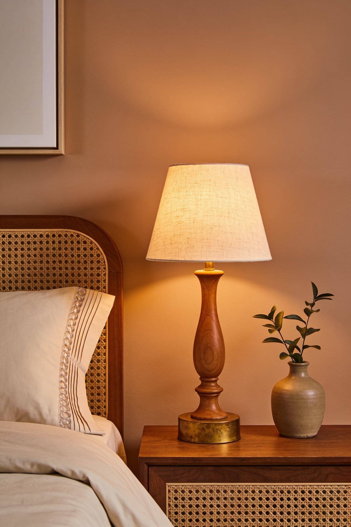 warm ceramic budget table lamp glowing on a wood nightstand