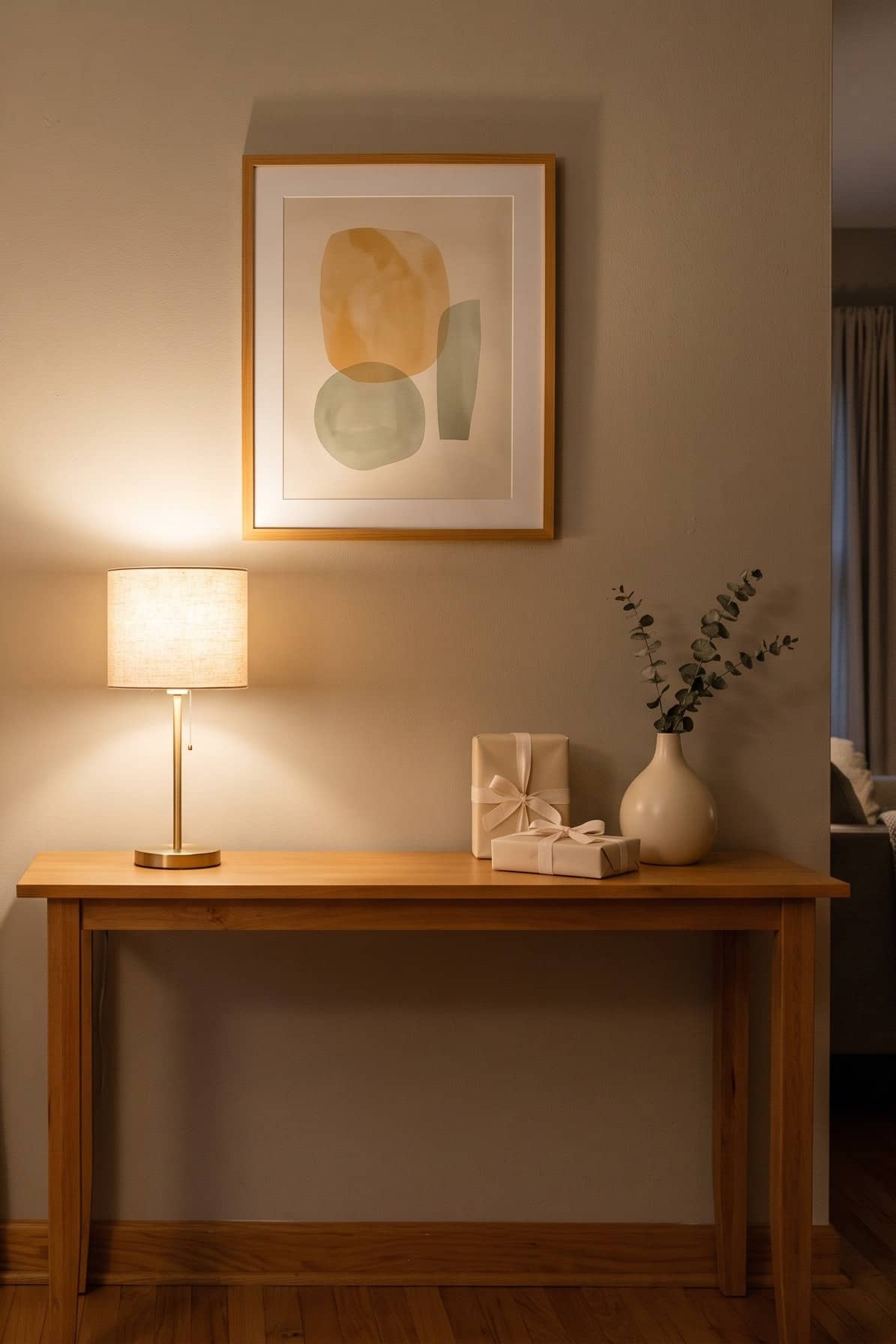 a rental living room in the evening with two linen wall sconces glowing beside a window with gold curtain brackets and a small cordless brass lamp on a console